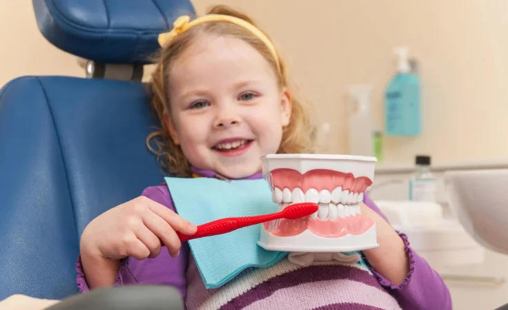 An infant or youngster clutching an electric toothbrush while reclining in an orthodontic armchair.